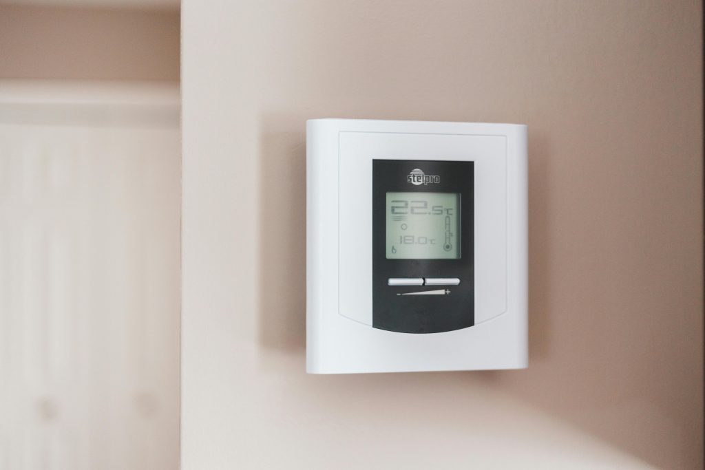 Close-up of a modern digital thermostat mounted on a wall, displaying temperature settings in Celsius.