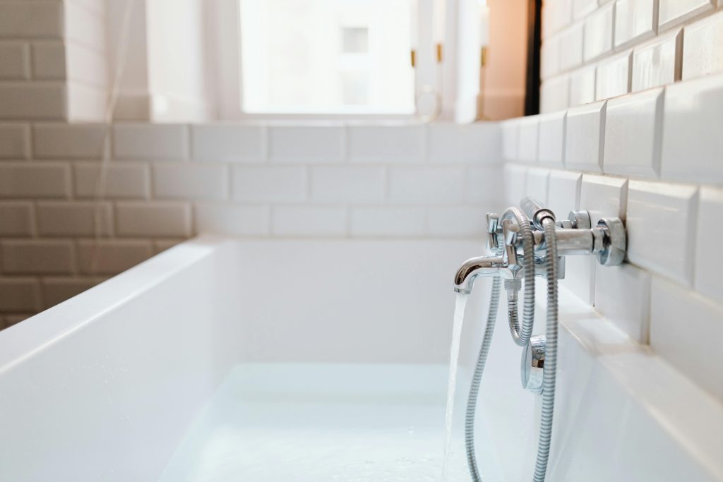 Stylish ceramic bathtub with modern stainless steel faucet in a sunlit bathroom.